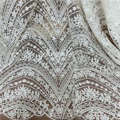 white lace fabric with an intricate design on it's edges and back side,