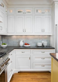 a kitchen with white cabinets and black counter tops