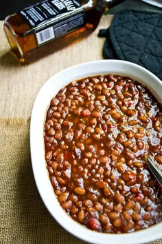 a white bowl filled with baked beans next to a bottle