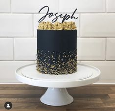 a black and white cake with gold sprinkles sits on top of a pedestal