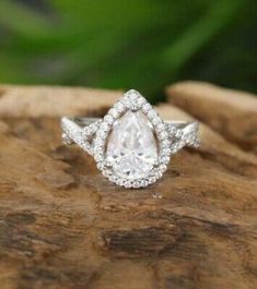 a pear shaped diamond ring on top of a rock