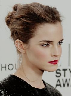 a woman with red lipstick on her face and hair in a high bun updo