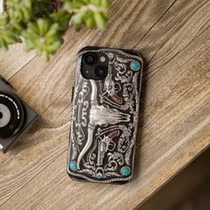 a cell phone case sitting on top of a wooden table next to a camera and plant