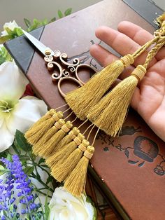 a pair of yellow tasseled earrings sitting on top of a book next to flowers