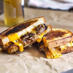 a grilled cheeseburger cut in half on a white plate with melted cheese