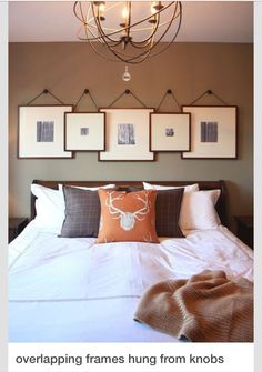 a bed with pillows and pictures hanging on the wall