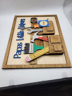 a wooden sign with tools on it sitting on top of a table