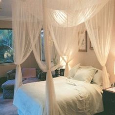 a bedroom with four poster bed and white curtains