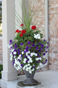 a metal vase filled with flowers sitting on top of a porch