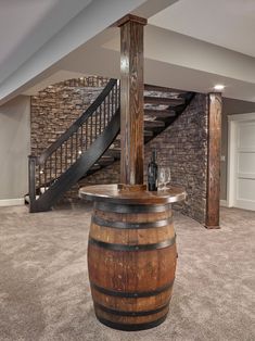 a wine barrel sitting in the middle of a living room next to a stair case