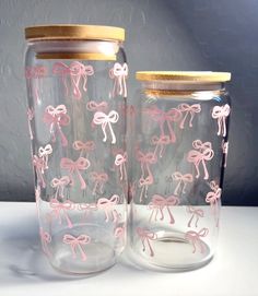 two glass jars with pink flamingos on them sitting side by side, one has a gold lid and the other is clear