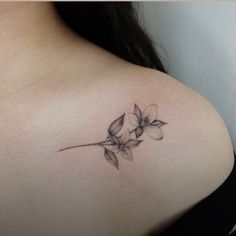 a woman's shoulder with a flower tattoo on the left side of her breast