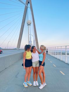 three girls standing on a bridge with their arms around each other