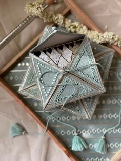 an origami box sitting on top of a table next to some string and flowers