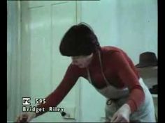 a woman in red shirt and black hat with headphones on standing next to mirror