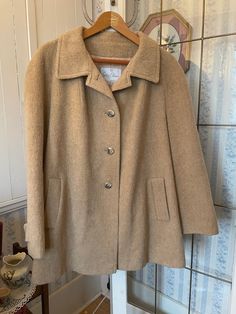 This lovely jacket by Surrey Classics, Canada, is made from a blend of 80 per cent wool, 10 per cent mohair and 10 per cent nylon - so warm and soft! - in classic camel beige. It has the original buttons on the front and matching buttons on the cuffs, two outside pockets, and is fully lined with light beige silky lining. The measurements, taken with the jacket lying flat, are: shoulder to shoulder, 20 inches; armpit to armpit, 24  inches; sleeves, 25 inches; length, 34 inches; bottom edge, 34 inches. In very good condition. Classic Cream Wool Coat With Long Sleeves, Classic Long-sleeved Cream Wool Coat, Beige Single Breasted Wool Coat For Fall, Beige Single-breasted Wool Coat For Fall, Classic Beige Outerwear For Fall, Beige Long Sleeve Wool Coat, Cream Wool Long Sleeve Outerwear, Classic Cream Pea Coat For Winter, Classic Cream Wool Coat For Winter