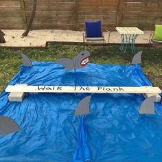 a blue tarp with sharks on it and a sign that says walk the plank