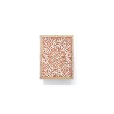 an intricately designed wooden plaque mounted on a white wall, with a square frame in the middle