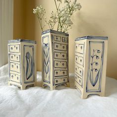 three blue and white vases sitting on top of a bed next to each other