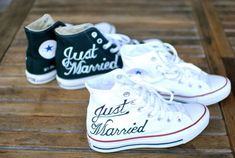 two pairs of white tennis shoes sitting on top of a wooden bench with the words just married written on them