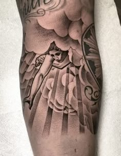 a man's arm with an angel and clouds tattoo on the side of his leg