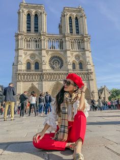 a woman sitting on the ground in front of a cathedral