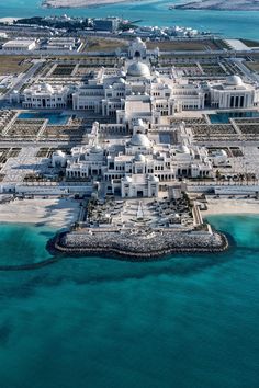 an aerial view of a large white building in the middle of blue water and land