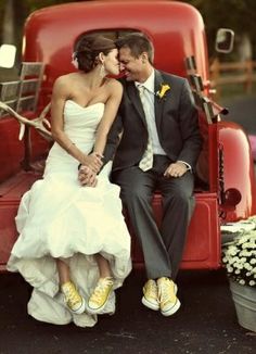 a bride and groom sitting in the back of an old red truck with yellow shoes