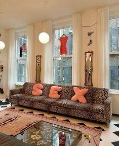 a living room filled with lots of furniture and large windows covered in leopard print pillows