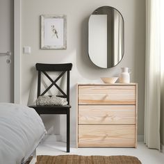 a bedroom with a dresser, mirror and chair