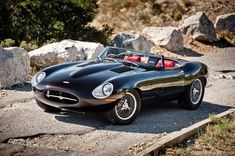 a black sports car is parked on the side of the road in front of some rocks