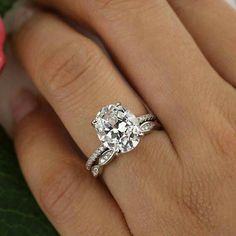 a woman's hand with a diamond ring on it and a rose in the background