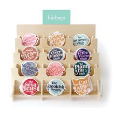 a display case with twelve badges in different colors and designs on the front, including one for children's book club