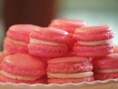 there are many pink and white cookies on the plate