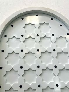 a circular window with black dots on it's side and white wall behind it