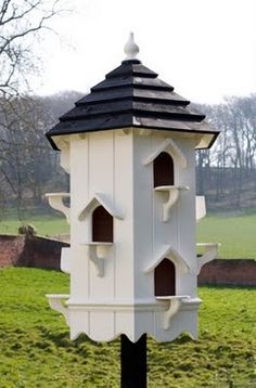 a white and black bird house sitting on top of a green field