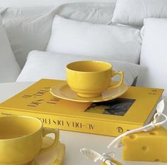 a yellow cup and saucer sitting on top of a book