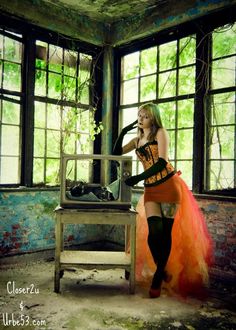 a woman in an orange and black corset is standing next to a chair