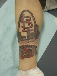 a man's leg with a st louis cardinals tattoo on it and the st louis arch in the background