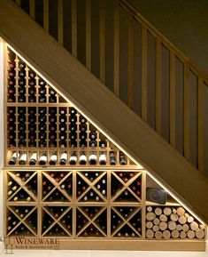 a wine rack under a stair case with lots of bottles in it and lights on the side