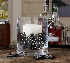 a candle is sitting in a glass with dices on the table next to it