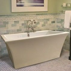 a bath tub sitting next to a sink in a bathroom under a framed picture on the wall