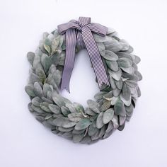 a wreath made out of green leaves with a bow on the front and back side