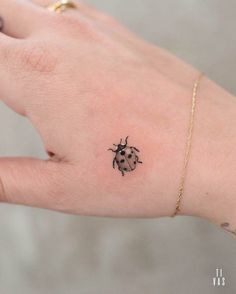 a ladybug tattoo on the left palm of a woman's right hand