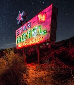 a neon sign that says star tv motel in front of the night sky with stars