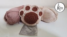 three balls of yarn sitting on top of a white table with a dog paw motif