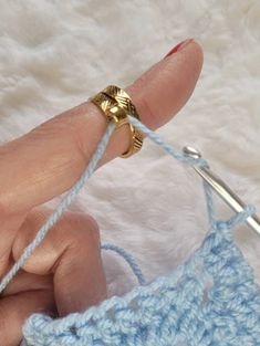 a crocheted ring is being held by someone's hand while they are knitting