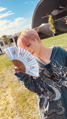 a girl with pink hair holding a fan in her hand and looking at the camera