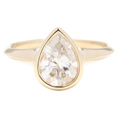 a yellow gold ring with a pear shaped diamond in the center and a thin band around it