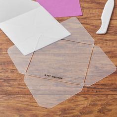 three pieces of clear plastic sitting on top of a wooden table next to a pair of scissors